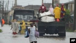Residentes cruzan una calle inundada, en Batabanó, tras el paso de Idalia por el occidente cubano.
