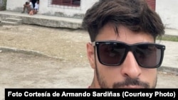 Armando Sardiñas, exprisionero político del 11J ; al fondo, Colegio Electoral en La habana durante las elecciones parlamentarias.