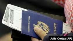 Una persona sostiene su pasaporte cubano antes de subir a un vuelo (Julio Cortez/AP/Archivo)