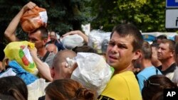 Residentes se reúnen para entregar donativos como medicamentos, ropa y pertenencias personales a sus familiares en los territorios ocupados por Rusia, en Zaporiyia, Ucrania. (AP Foto/Andriy Andriyenko)