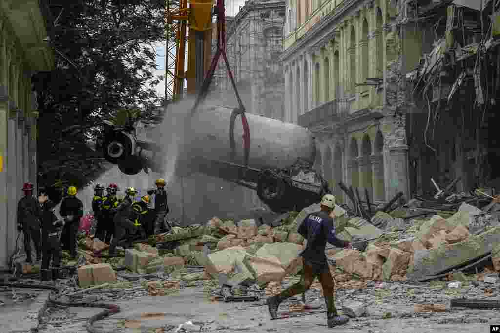 Los bomberos rocían con agua un camión cisterna para enfriarlo mientras lo retiran del lugar de una explosión letal que dañó el hotel Saratoga en La Habana, el viernes 6 de mayo de 2022. (AP Foto/Ramón Espinosa)