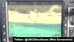 Dos balseros cubanos alzando una bandera mientras piden ayuda fueron rescatados por la Guardia Costera.