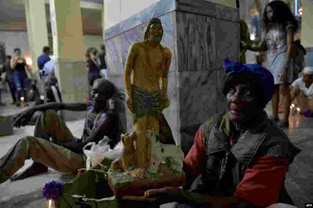 Un peregrino lleva una estatuilla de Babalú Ayé, la imagen sincrónica de San Lázaro en los ritos afrocubanos. Yamil Lage/AFP