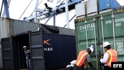 Fotografía que muestra agentes policiales mientras inspeccionan un contenedor donde se encontraron dos aviones Mig - 21