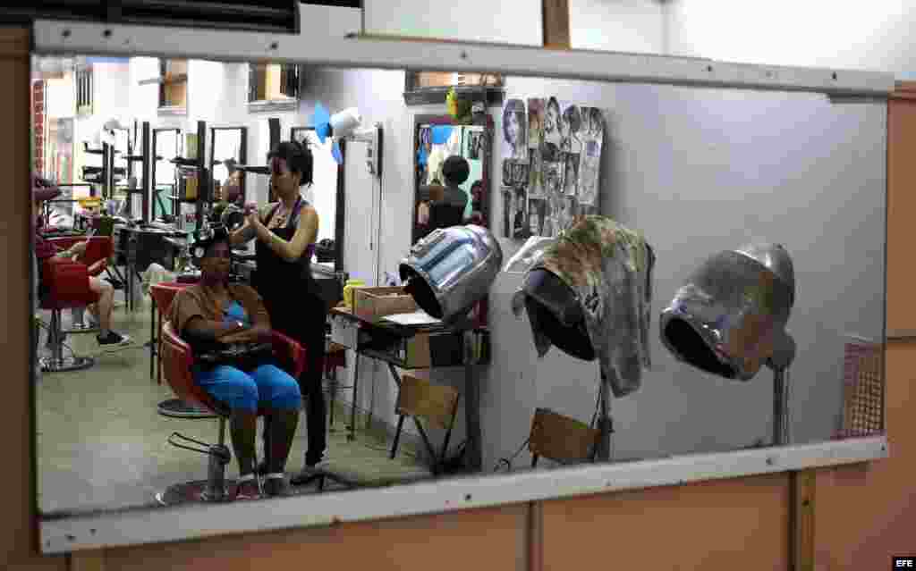 Una peluquera atendiendo a una clienta en un local rentado al estado, en La Habana.