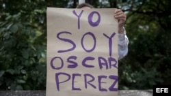 Una mujer sostiene un cartel en el que se lee "Yo soy Óscar Pérez" frente a la morgue donde permanece su cuerpo.