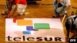 Trabajadores dan los últimos detalles a un cartel publicitario del canal latinoamericano de televisión "Telesur".