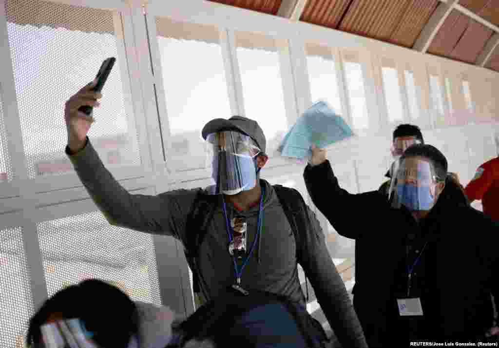 Mikel Riviaux y Pedro Luis Ruiz migrantes cubanos bajo el Programa de Protección de Migrantes (MPP) por sus siglas en inglés caminan el puente de la frontera internacional El Paso Norte desde Ciudad Juárez, México hacia El Paso Texas, Estados Unidos para poder continuar sus trámites de asilo, mientras se toman un selfie. Foto: tomada el 11 de marzo de 2021 por REUTERS/José Luis González.