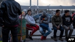 Migrantes esperan a la entrada del Puente Internacional Paso del Norte, en Ciudad Juárez.