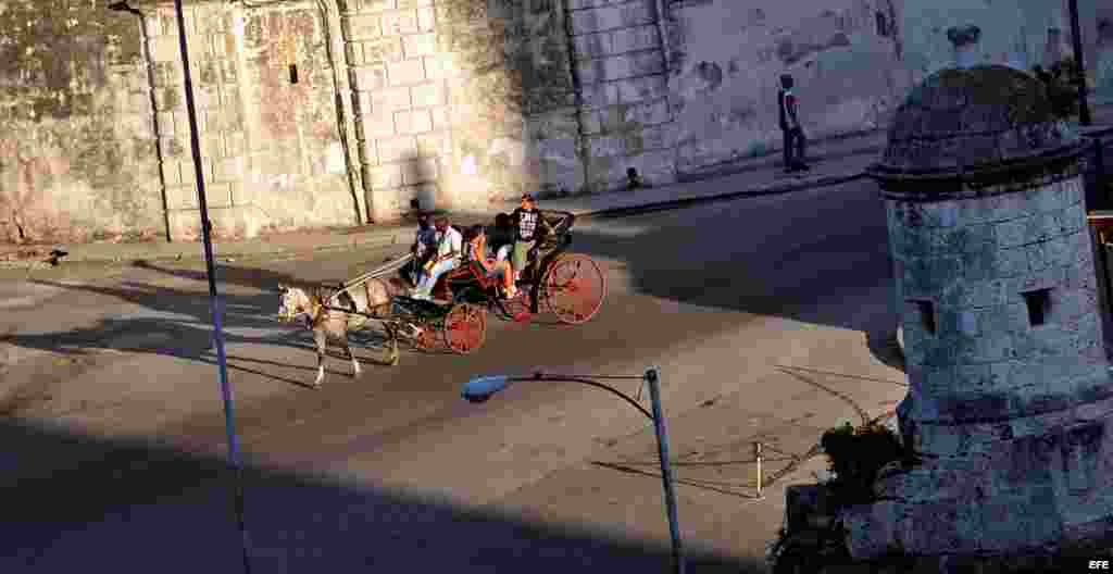 Varios turistas pasean en un coche de caballos por una avenida de La Habana Vieja