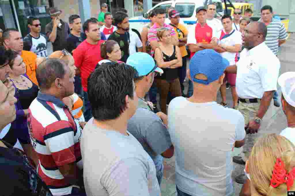 Un funcionario panameño de Migración (i) explica a los cubanos varados en Paso Canoas (Panamá) hoy, miércoles 10 de febrero de 2016, el procedimiento que les permite comprar el boleto de avión, por 523,50 dólares cada uno, para viajar a México.