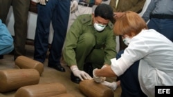 Archivo (2005) - Agente policial, junto a una agente de criminalística examinan la marihuana para ser quemada en un horno de una fábrica de acero en la provincia de Holguín, Cuba.