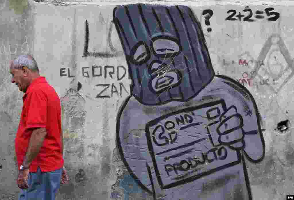Un hombre camina junto a un grafiti alusivo a la libreta de abastecimiento en una calle de La Habana (Cuba), este viernes, 20 de enero de 2017, día en que Donald Trump asume la presidencia de EEUU. Washington y La Habana han desarrollado una frenética actividad bilateral en las últimas semanas, pues con la salida de Barack Obama de la Casa Blanca y la llegada de Trump la continuidad del deshielo iniciado en el 2014 se tiñe de incertidumbre, dado que el nuevo mandatario ha insistido en que no está de acuerdo con este proceso.  