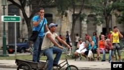 Dos hombres viajan en un triciclo por la zona colonial de La Habana (Cuba).