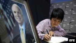 Una mujer escribe un mensaje en el libro de condolencias situado en la embajada de EEUU en Hanoi por la muerte del senador John McCain.