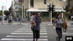 Una pareja israelí corre tras escuchar las sirenas de alarma en Tel Aviv, Israel. Archivo.