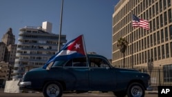 Foto Archivo. Un carro con la bandera cubana pasa frente a la Embajada de Estados Unidos en Cuba.
