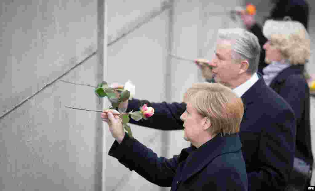 La canciller de Alemania, Angela Merkel (i) junto al alcalde de Berlín, Klaus Wowereit (2-d) colocando flores en un segmento de lo que fuera el Muro de Berlín.