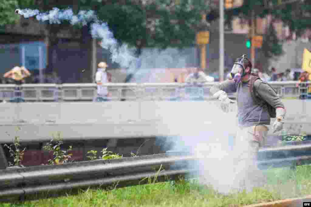 Un manifestante devuelve una granada de gases lacrimógenos lanzada por miembros de la Policía Nacional Bolivariana (PNB) durante una protesta hoy, miércoles 18 de mayo de 2016, en la ciudad de Caracas (Venezuela).