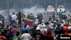Manifestantes enfrentan los vehículos militares, cerca de la base La Carlota, en Caracas.