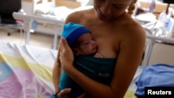 Zeudi Catamo carga a su bebé Derwin Mora.