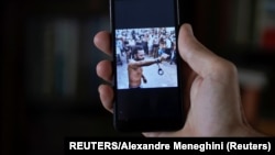 Un hombre que no quiso ser identificado muestra en su teléfono al rapero contestatario Maykel Castillo El Osorbo. (REUTERS/Alexandre Meneghini)