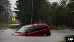 En esta foto del viernes, una minivan abandonada se ve semisumergida en una carretera inundada cerca de New Bern, Carolina del Norte