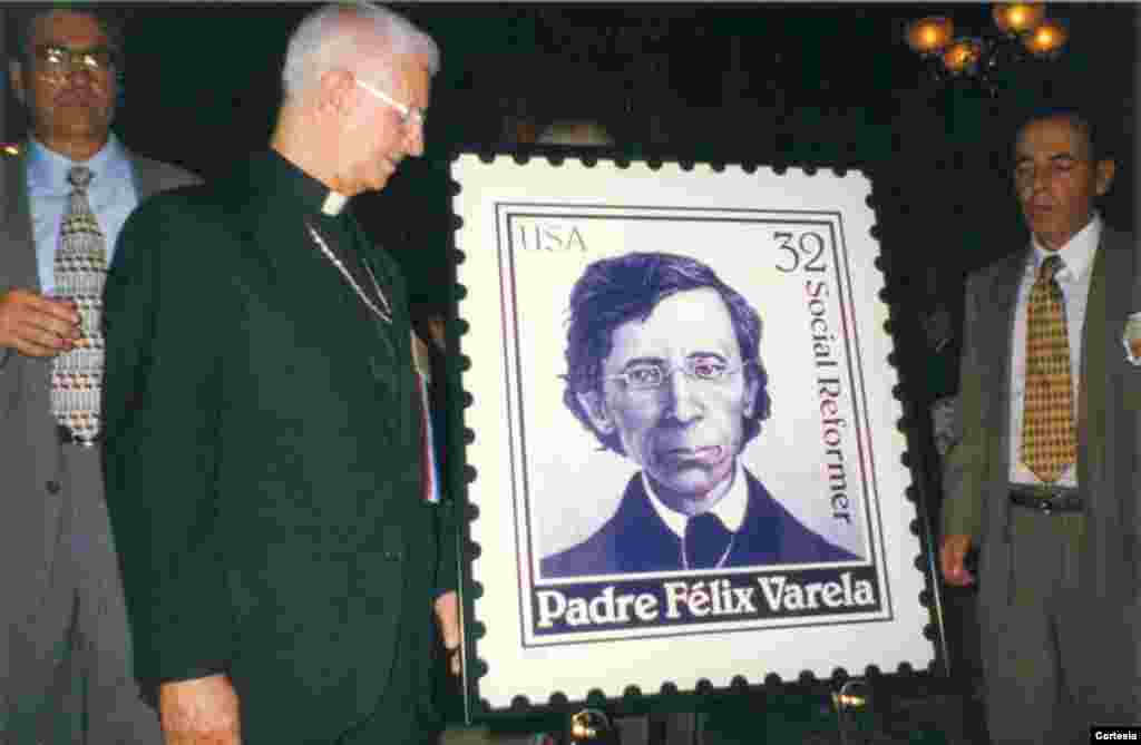 Padre Agustin Roman posa junto a un sello conmemorativo de la vida del padre Félix Varela, un sacerdote cubano quien fue nombrado venerable por el Vaticano.