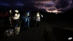 Migrantes solicitantes de asilo se envuelven en mantas para protegerse del viento y la lluvia mientras esperan a ser procesados tras cruzar la frontera con México, en Jacumba Hot Springs, California.