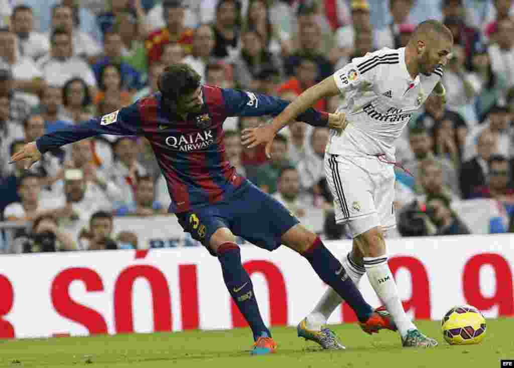 El delantero francés del Real Madrid Karim Benzema (d) controla el balón ante el defensa del FC Barcelona Gerard Piqué (i).
