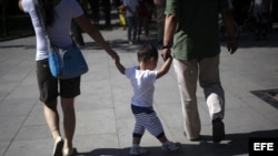 Padres chinos llevan de la mano a su hijo en un parque de Pekín (China).
