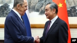 El ministro ruso de Exteriores, Serguéi Lavrov (I) y el ministro chino de Exteriores, Wang Yi, se estrechan la mano antes de una reunión en Beijing, China. (Servicio de prensa del Ministerio ruso de Exteriores via AP)