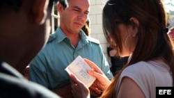 Una mujer conversa con un oficial de Inmigración y Extranjería en la puerta de una oficina de esa institución en La Habana (Cuba).