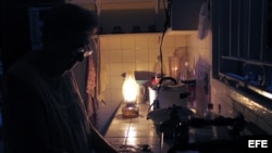 Una mujer lava los platos iluminada por una lámpara de queroseno durante un apagón. (EFE/Archivo)