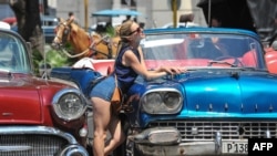 Una turista posa para una foto en La Habana Vieja. Al fondo, uno de los carruajes que pasean a los visitantes extranjeros.