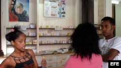 Tres jovenes conversan en una farmacia en La Habana,Cuba.