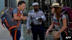 Un policía guía a turistas en una calle de La Habana en medio de la pandemia de coronavirus.