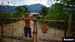 El campesino Javier Tamayo, 55, posa junto a su nieto en su casa en la Sierra Maestra. REUTERS/Alexandre Meneghini