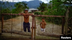 El campesino Javier Tamayo, 55, posa junto a su nieto en su casa en la Sierra Maestra. REUTERS/Alexandre Meneghini