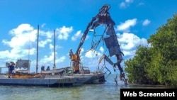 Un casco de acero de 18 pies es sacado de los manglares de las Marquesas. (Foto: Celia Hitchins/Monroe County Marine Resources Office)