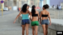 Tres mujeres caminan por el malecón.