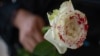 Una mujer sostiene una rosa "ensangrentada" en señal de luto por los feminicidios. (Pedro Pardo / AFP)